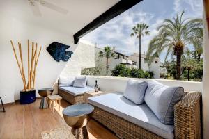 a living room with a couch and a balcony with palm trees at Luxurious apartment in Puente Romano, Marbella (Golden Mile) in Marbella