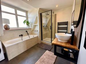 a bathroom with a tub and a sink and a shower at Geschmackvolle Ferienwohnung in Markkleeberg in Markkleeberg