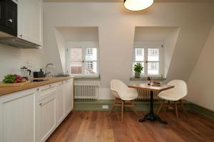 a kitchen with white chairs and a table and two windows at Palmbräu Altstadt Appartments in Heidelberg