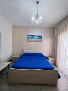 a bedroom with a blue bed and a chandelier at Albergo Primavera in Porto Cesareo
