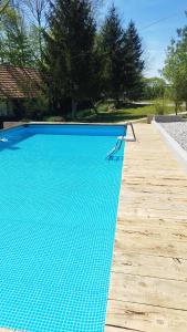 einen großen blauen Pool mit Holzterrasse in der Unterkunft KUĆA ZA ODMOR/PROSLAVE in Lukinić Senovec