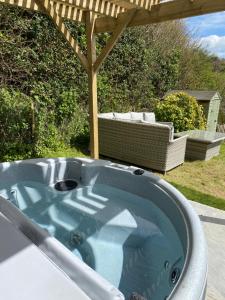 a hot tub sitting under a pergola at ‘The Nest’ A beautiful cottage in Devon in Axminster