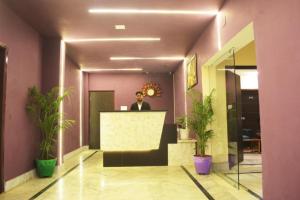 a man standing at a counter in a lobby at Goroomgo Luxury Star Inn Near Sum Hospital in Bhubaneshwar