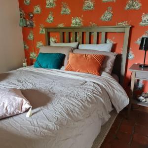 Cama en habitación con pared de color naranja en La Longère d'Ecottes, en Licques