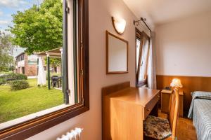een kamer met een raam, een bureau en een bed bij Agriturismo Ca' Marcello in Mira