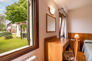 Habitación con ventana, escritorio y cama. en Agriturismo Ca' Marcello en Mira