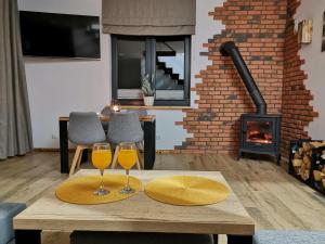 two glasses of wine on a table in a living room with a fireplace at Chillout House Serwy in Serwy