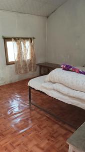 ein Schlafzimmer mit einem Bett, einem Fenster und einem Holzboden in der Unterkunft Chital lodge in Chitwan