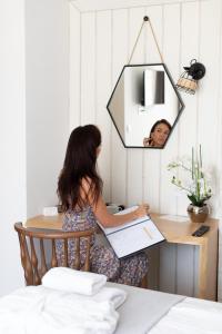 a woman sitting at a table in front of a mirror at Garni Hotel Casa di Sofia in Budva