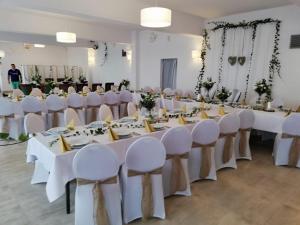 DługieにあるPensjonat Długie Nowicki Rooms & Apartmentsの白いテーブルと椅子が備わる宴会場