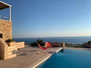 a villa with a swimming pool and two chairs on a patio at Patio Villas Complex in Stoupa