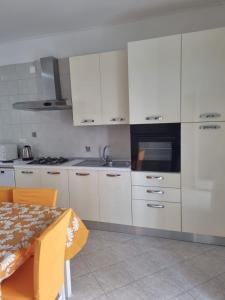 a kitchen with white cabinets and a table and a microwave at Casa vacanza yolo in Macerata Campania