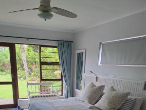 a bedroom with a bed and a ceiling fan at Plettenberg Bay 7 BUNKER AVENUE in Plettenberg Bay