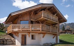 a house with a large deck on top of it at Chalet neuf La Perle du Perron in Cordon