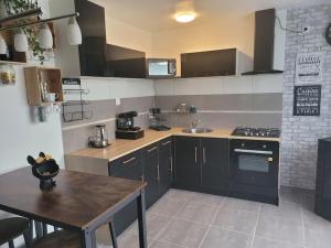 a kitchen with black cabinets and a wooden table at petite maison cosy en duplex in Éguelshardt