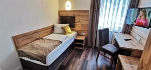 ゾルタウにあるHeidehotel Soltauer Hofのベッドとデスクが備わる小さな客室です。