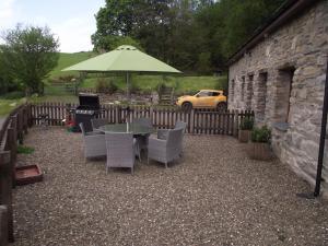 eine Terrasse mit einem Tisch, Stühlen und einem Sonnenschirm in der Unterkunft Cae Coryn Cottages, Snowdonia ( Troed y Graig ) in Bala