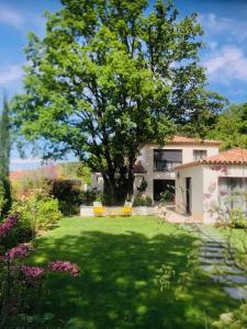 um quintal com uma grande árvore em frente a uma casa em Villa Francine em Bouc-Bel-Air