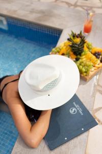 Una donna in piscina con un cappello e un piatto di cibo di Garni Hotel Casa di Sofia a Budua