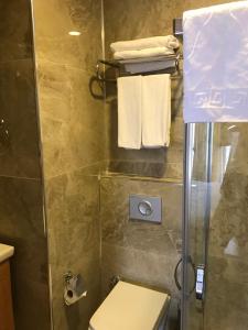 a bathroom with a shower and a toilet and towels at Carpe Diem Hotel in Ayvalık