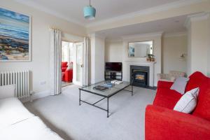 uma sala de estar com um sofá vermelho e uma mesa em Church Farmhouse - Castle View (4 bedroom) & Church View (2 bedroom) em Castletown