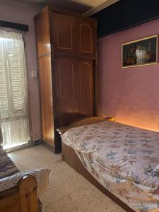 een slaapkamer met een bed en een houten kast bij شقه مفروشه سوبر لوكس بميامى الاسكندريه in Alexandrië