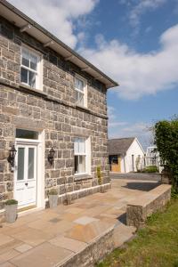 uma casa de tijolos com uma porta branca e um pátio em Church Farmhouse - Castle View (4 bedroom) & Church View (2 bedroom) em Castletown