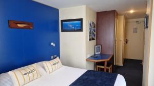 Pokój hotelowy z dużym łóżkiem i niebieską ścianą w obiekcie Hotel Le Marin w mieście Auray