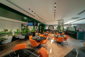 a restaurant with orange chairs and tables in a room at Dostyk Business Hotel in Aktau