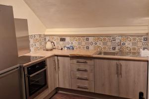 a kitchen with wooden cabinets and a sink and a stove at Eta's Manor @ Brooklands in Maryport