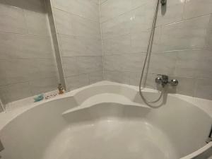eine weiße Badewanne mit Dusche im Bad in der Unterkunft Cozy 8-Person Home in Vienna Located at Haberlgasse 82 N1 in Wien