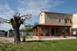 une maison en pierre avec un arbre dans une cour dans l'établissement Holiday Home ZORA, à Višnjan