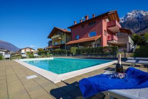 een zwembad met een fles wijn naast een gebouw bij Residence Girasole Casa Rossa B in Colico