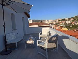 einen Balkon mit Stühlen, einem Sonnenschirm und einem Tisch in der Unterkunft Casa Ghirthalos in Nuoro