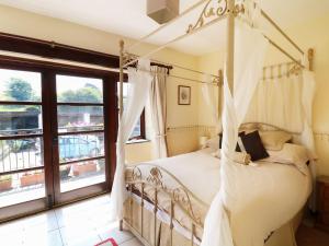 ein Schlafzimmer mit Himmelbett und großem Fenster in der Unterkunft The Corn Tallet in Bideford + 21 Fotos