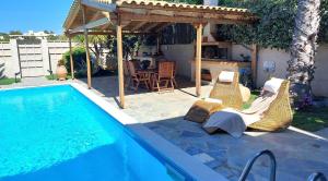 een zwembad met stoelen en een pergola naast een huis bij Luxury apartment SEA HELM with private swimming pool and BBQ in Lagonissi
