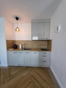 cocina con armarios blancos y suelo de madera en Apartamenty Julia APARTAMENTY OZONOWANE en Ustronie Morskie