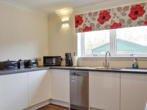 a kitchen with white cabinets and a sink and a window at Lady Jane Cottage in Fettercairn
