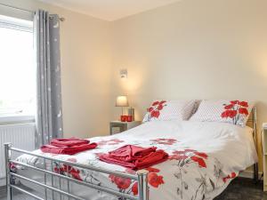 a bedroom with a bed with red towels on it at Lady Jane Cottage in Fettercairn
