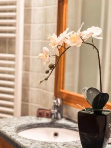 a vase with white flowers on a bathroom sink at Green Park Studio Courmayeur in Courmayeur