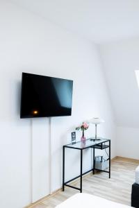 einen Flachbild-TV an der Wand im Wohnzimmer in der Unterkunft Modernes Apartment in der Innenstadt in Würzburg