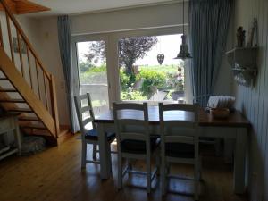 ein Esszimmer mit einem Tisch, Stühlen und einem Fenster in der Unterkunft Kleine Scholle in Neuharlingersiel