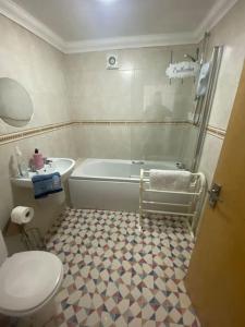 a bathroom with a tub and a toilet and a sink at The Garden Flat in Paignton