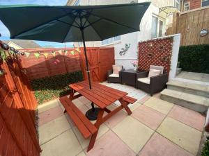a wooden picnic table with an umbrella on a patio at The Garden Flat in Paignton