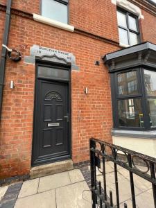 una puerta negra en el lateral de un edificio de ladrillo en Burleigh House - 3 Bed House, en Leicester