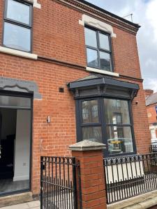 een bakstenen gebouw met ramen en een zwart hek bij Burleigh House - 3 Bed House in Leicester
