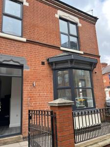 un edificio de ladrillo con ventanas y una valla negra en Burleigh House - 3 Bed House, en Leicester