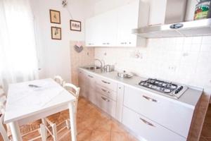 uma cozinha com armários brancos, uma mesa e um fogão em Villa Tharros em Capoliveri