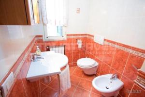 uma casa de banho com um lavatório branco e um WC. em Villa Tharros em Capoliveri