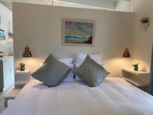 um quarto com uma cama branca e 2 almofadas em Gorgeous, private cottage in prestigious Newlands. na Cidade do Cabo